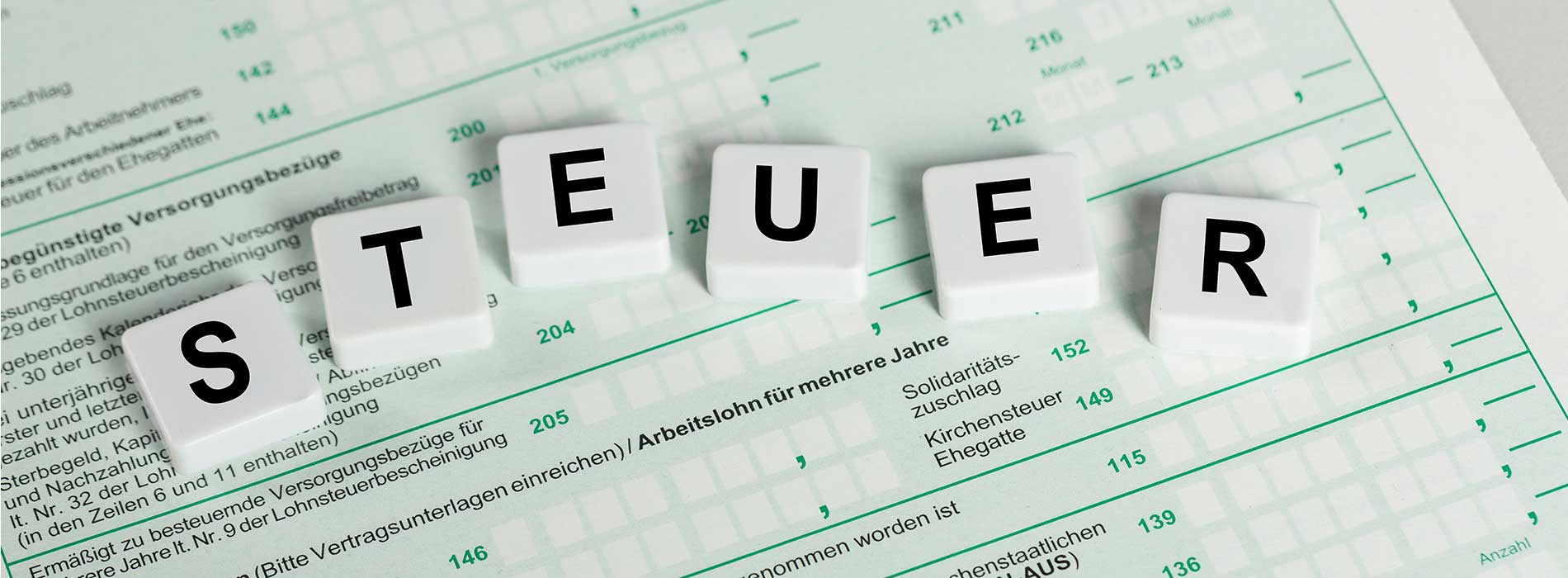 Schwarz-weiße Nahaufnahme von Buchstabenplättchen mit dem Wort 'STEUER' auf einem Formular